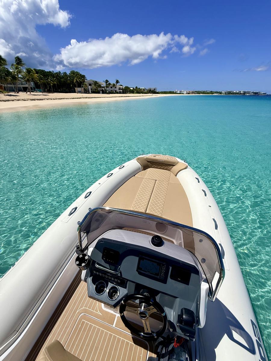 Mouillage devant Meads Bay, à Anguilla : le poste de pilotage et l'avant du semi-rigide, la longue plage de sable blanc et ses cocotiers